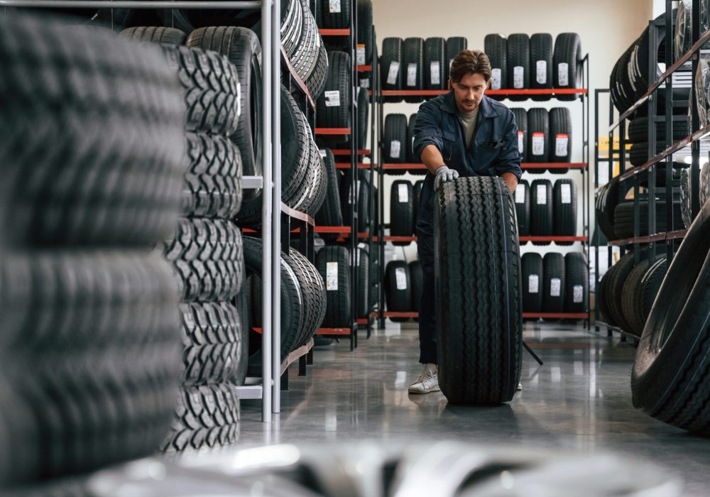 Rolling the wheel. Man is in the tire fitting car service.